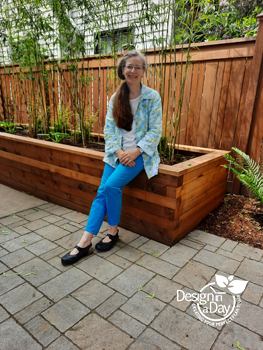 pictured Carol Lindsay founder of Landscape Design in a Day sitting on cedar planter. Paver is Victoriana by Belgard, Planter designed by Victor and Carol, Bamboo is Fargesia robusta and new fence by Cascade